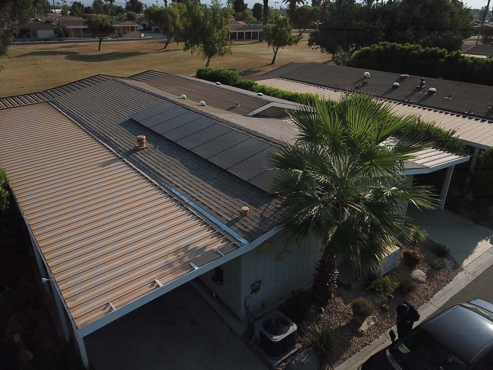 Aerial view of a manufactured home in Southern California with solar panels installed on the roof, surrounded by landscaping and a palm tree, showcasing a recent solar installation by Mobile Home Power.